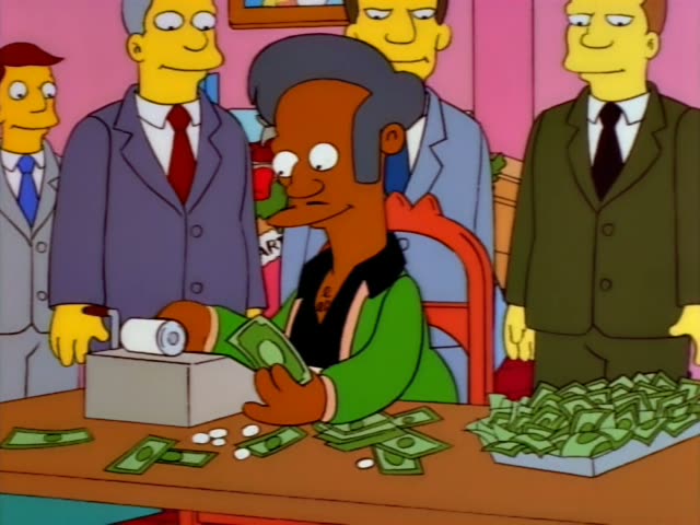 Apu sits at a desk counting cash while three men in suits stand behind and to the sides of him