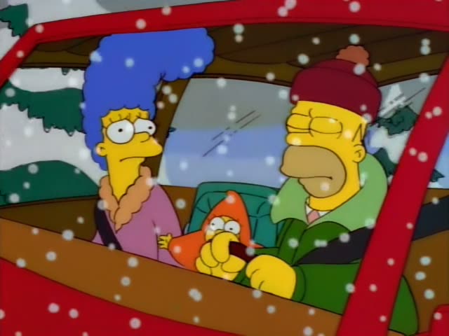 Homer and Marge sit in the front of a red car with baby Maggie in an orange hood and holding a pacifier in the back seat