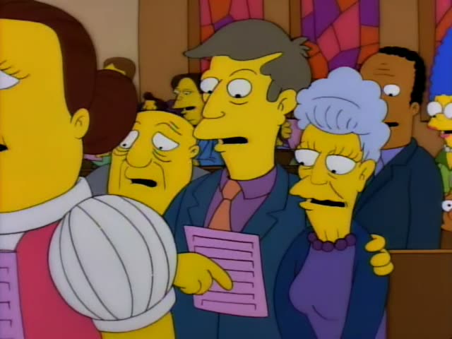 Principal Skinner and Mrs. Krabappel stand with Sideshow Bob, who has a huge mane of red hair and a red moustache…