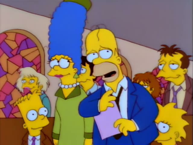Homer stands beside Marge, who has a tall blue beehive, while Bart, Lisa, and a brown-haired man in a suit crowd around them…