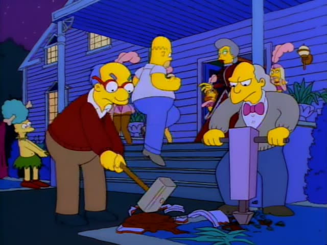 Mr. Burns works a jackhammer on the lawn of a blue house while a bespectacled man in a red sweater swings a sledgehammer…