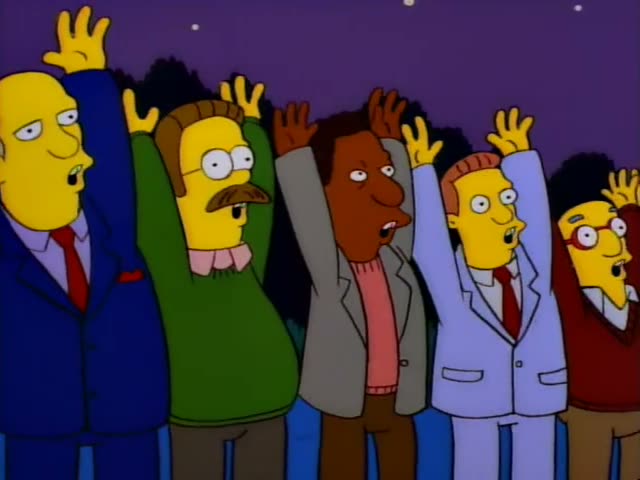Ned Flanders in his green sweater and Carl in his grey jacket and pink sweater stand with a bald man in a navy suit and red…