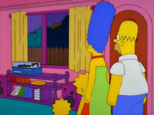Homer and Marge stand in the pink living room beside a red arched doorway, with Lisa visible at the bottom edge, as a man…