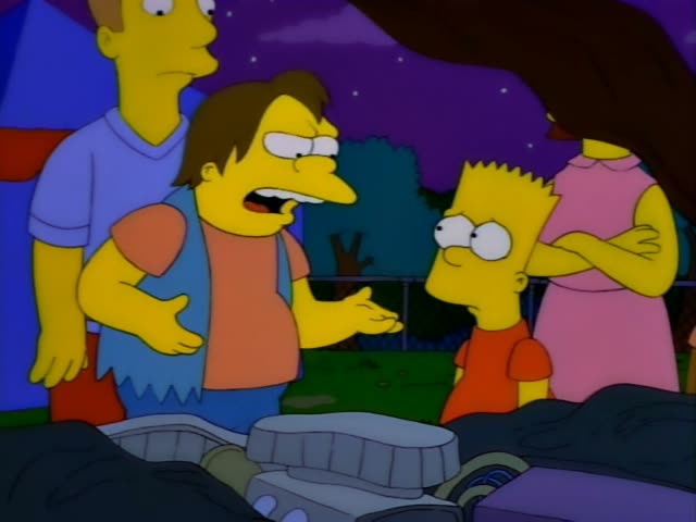 Nelson confronts Bart, the spiky-haired boy in an orange shirt, at night in a grassy yard by a chain-link fence…