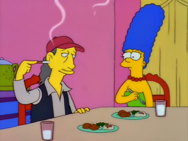 Marge Simpson sits at a dining table across from a thin, long-haired man in a red baseball cap and dark vest, who is not one…