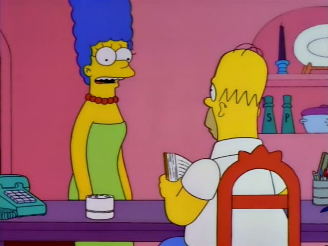 Homer and Marge are in a pink room with a purple desk, red flowers in a pot, a teal telephone and a monkey figurine
