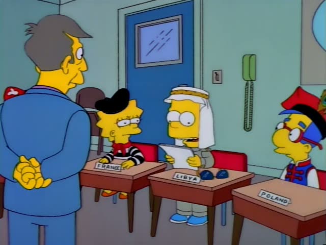 Principal Skinner stands at the left of a classroom with desks labeled France, Libya, Poland, Mexico, Trinidad and Japan