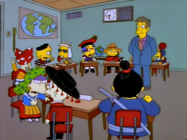 Principal Skinner stands at the front of a classroom beneath a Model U.N. Club banner, holding a flag, while students…