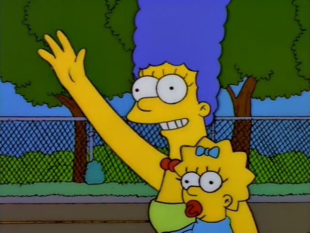 Marge Simpson and baby Maggie stand outdoors in front of a chain-link fence and green trees