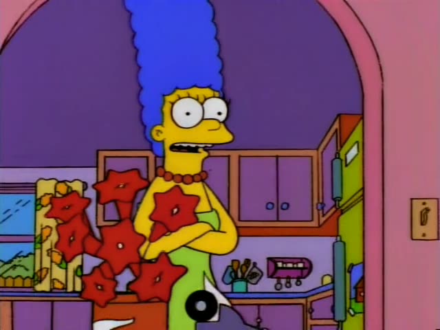 Marge Simpson stands with arms crossed in the arched doorway of the pink living room, next to a potted plant with red…