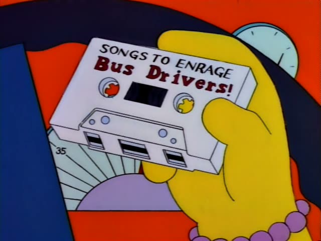 Otto steers while holding up a cassette labeled "Songs to Enrage Bus Drivers!" as passengers ride along