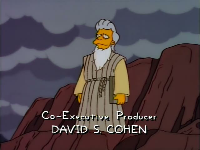 An elderly bearded man in a long striped robe, who does not match any regular character, stands on a rocky red cliff…