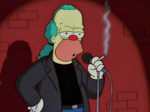 Krusty the Clown stands at a microphone on a wooden stage in a black jacket and black shirt, with a cigarette in his hand…