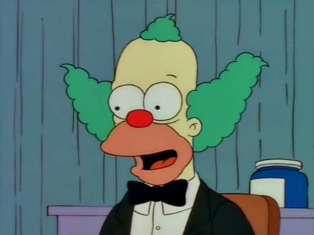 Krusty the Clown sits in a black bow tie and tuxedo jacket at a desk with a blue jar, first talking and then pausing…