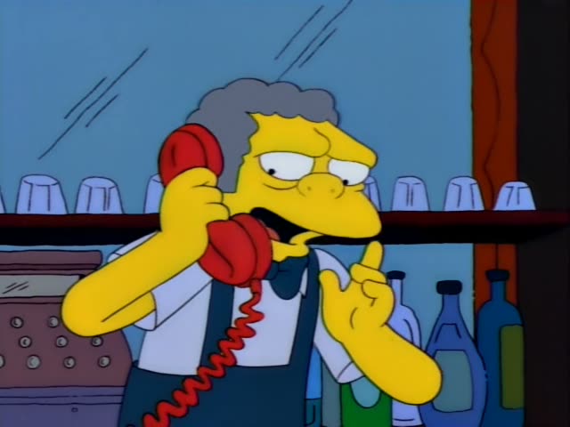 Moe stands behind the bar holding a red telephone receiver to his ear while talking