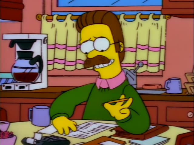 Ned Flanders sits at a kitchen table beside a woman with curly orange-red hair and a pink top, while a coffee maker…