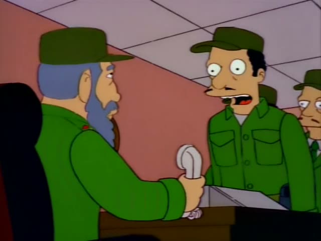 Homer sits beside Mr. Burns and another man in a white shirt on a blue-carpeted living room set, while a bearded leader…