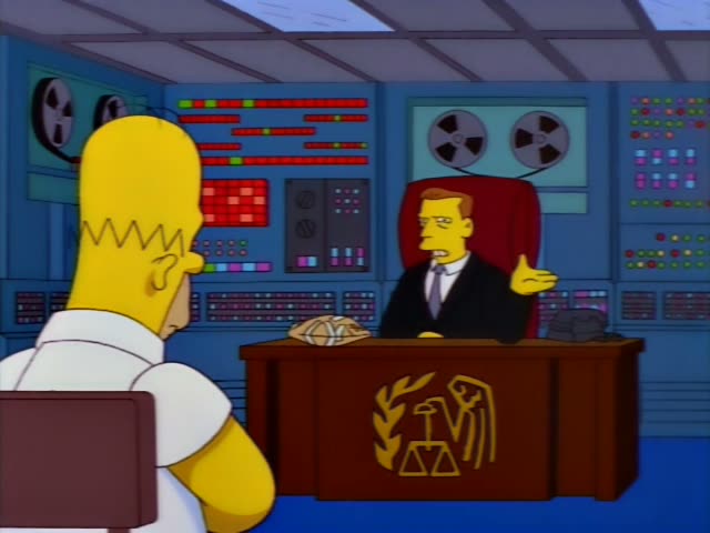 Homer stands with his back to the viewer facing a man in a dark suit and grey tie with swept-back reddish hair, seated…