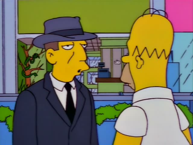 Homer Simpson stands outside a green storefront with a cash register visible through the window and hedges…