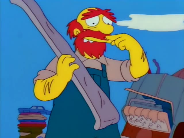 Lisa stands beside a junkyard of old cars and piled debris, watching a red-bearded man in blue overalls with a bandaged leg