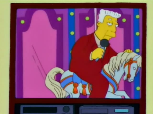 Kent Brockman holds a microphone while riding a white carousel horse with a blue saddle and orange trim