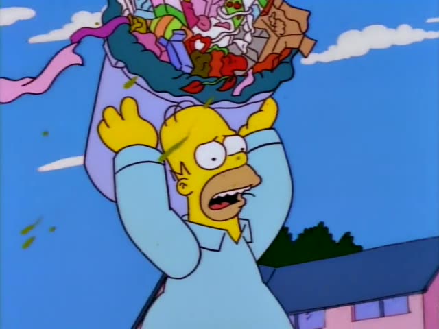 Homer Simpson carries an overflowing garbage bag over his head down a suburban street lined with pink and tan houses, a red…