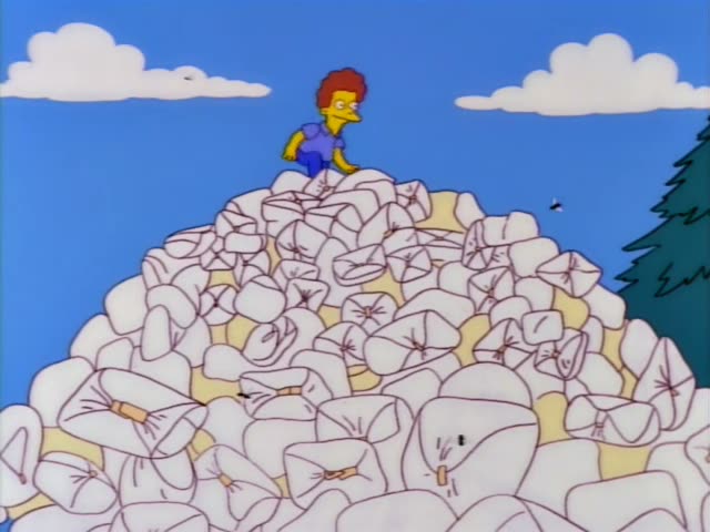 A red-haired boy in a purple shirt and blue pants stands atop a huge pile of white diapers on a sunny day, first watching…