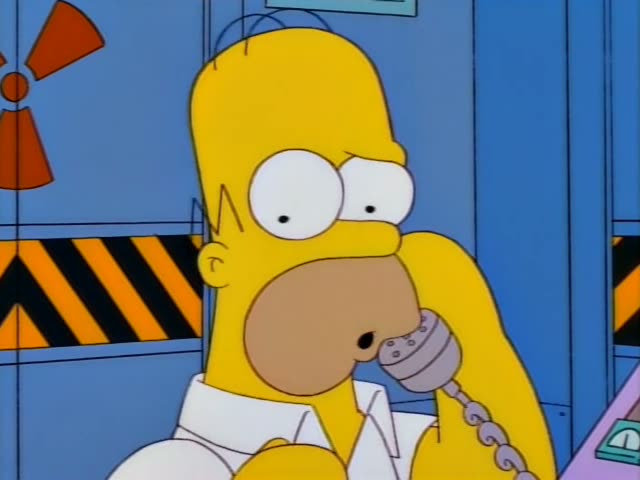 Homer stands before a blue wall with a radiation warning sign and a hazard-striped panel, holding a grey telephone receiver…