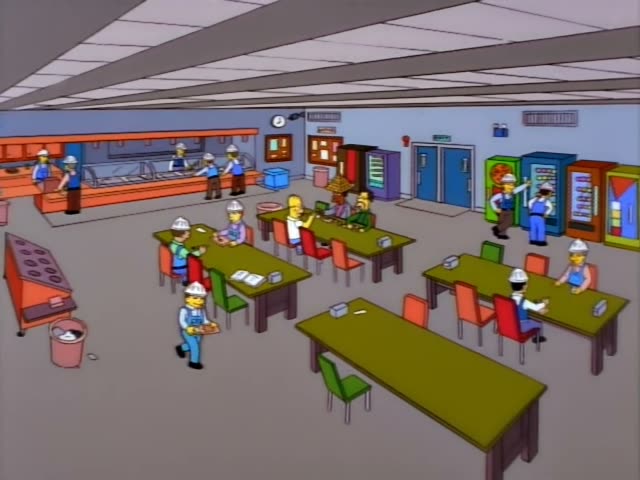 In a factory cafeteria with orange serving counter, vending machines, and olive-green tables, Homer Simpson sits in a white…