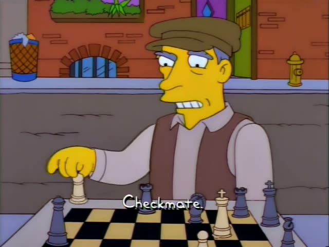 A grey-haired man in a flat cap and brown vest plays chess with a mustached man in a white embroidered shirt, first…