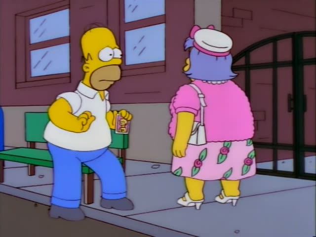 Homer Simpson stands on a sidewalk beside a green bench in front of a brick building with an arched iron gate, while a heavy…