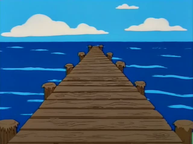 Homer first stands behind an orange podium with microphones on a street, then rides inside an orange box along a long wooden…