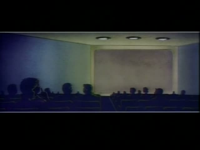 In a dim, blue-tinted animated movie theater, silhouetted audience members sit in rows of seats, with a large blank screen…