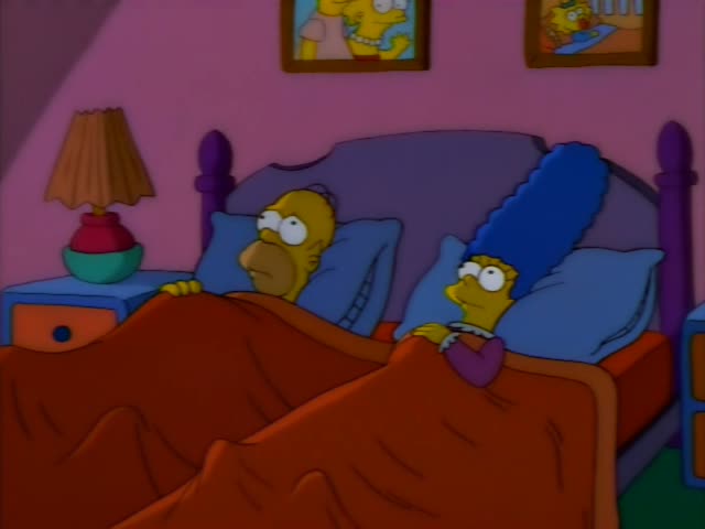 Homer and Marge Simpson lie side by side in bed under orange blankets in their pink bedroom, with a lamp on the blue…