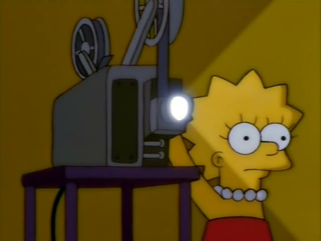 Lisa stands beside a purple-legged projector in a yellow room and works its lens while its light beam shines out