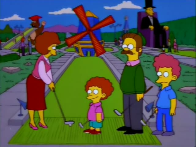 Ned Flanders in his green sweater and moustache stands with a woman in a pink vest and red skirt who has a curly auburn…