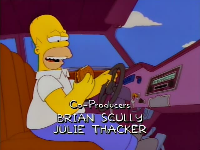 Homer Simpson sits behind the wheel of a pink car, eating a sandwich and steering as he chews