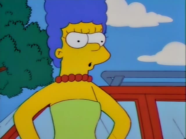 Marge Simpson stands with hands on hips in a front yard, scowling, while Bart Simpson and a brown-haired boy in a red scarf…