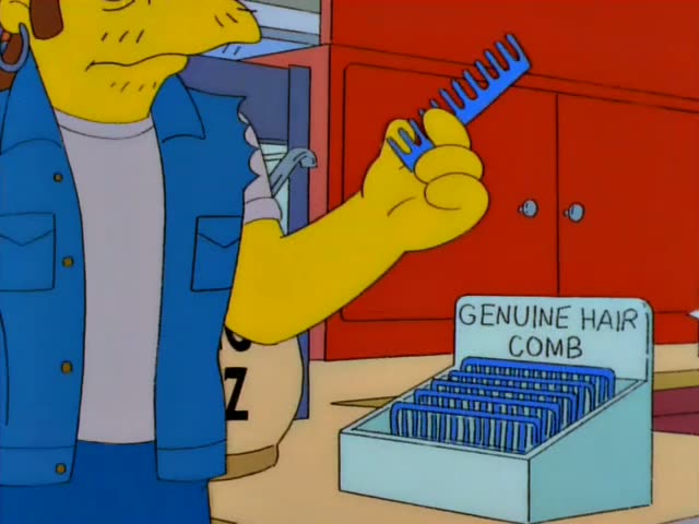 A scruffy brown-haired man in a blue denim vest, grey shirt and hoop earring stands at the Kwik-E-Mart counter…