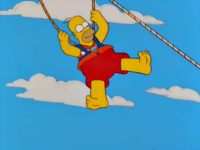 Homer dangles from ropes against a bright blue sky dotted with clouds while Marge and Lisa watch from a platform at lower…