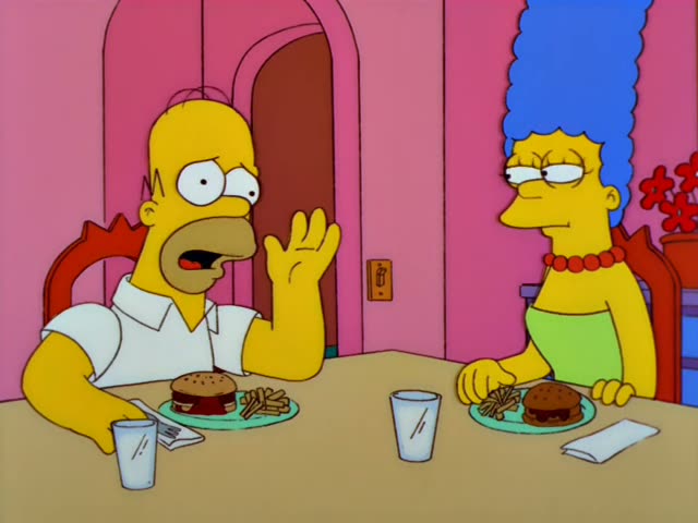 Homer Simpson and Marge Simpson sit across a pink-walled dining table, each with a hamburger, fries and a glass of water…