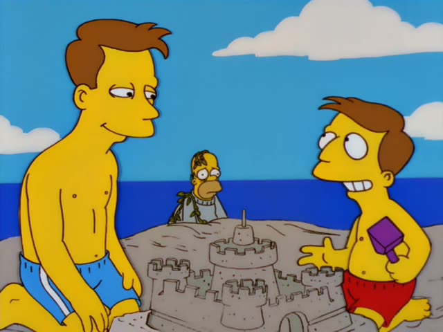 Homer watches from behind a large sandcastle on a sunny beach, while a shirtless brown-haired man in blue swim trunks kneels…