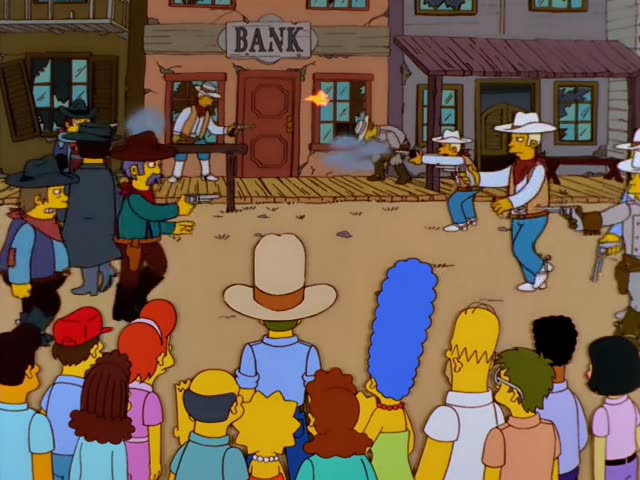 Homer, Marge, Lisa, Bart and Maggie stand with a crowd on a wooden boardwalk in a Wild West town, watching a gunfight…