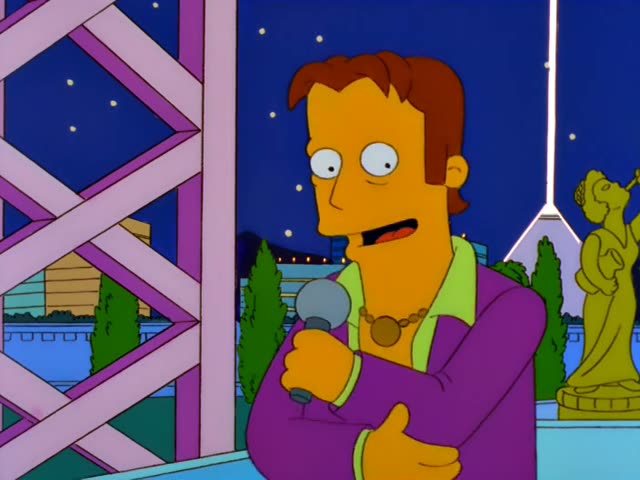 Troy McClure speaks into a microphone beside a lattice tower, then gestures as a crowd gathers below
