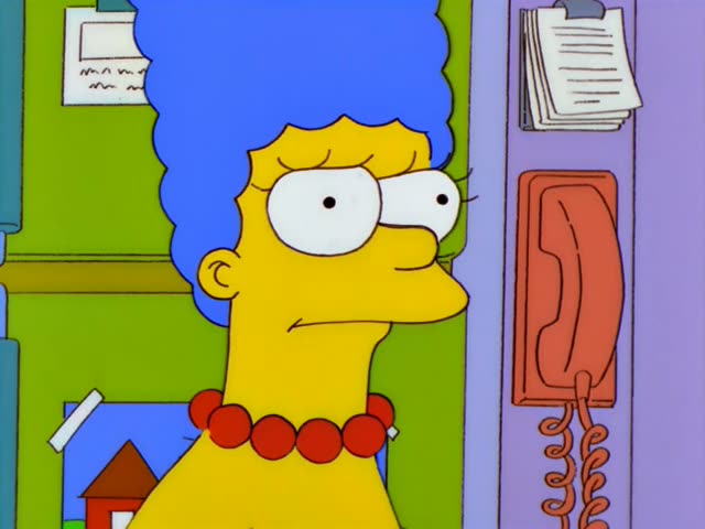 Marge Simpson stands beside a wall phone and speaks, then falls silent with a worried look