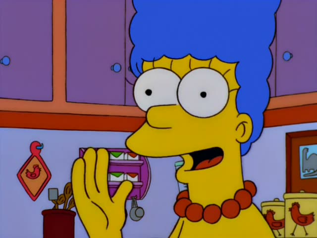 Marge is in the Simpson kitchen, first looking startled with a hand at her mouth, then pulling a small red rooster pot…