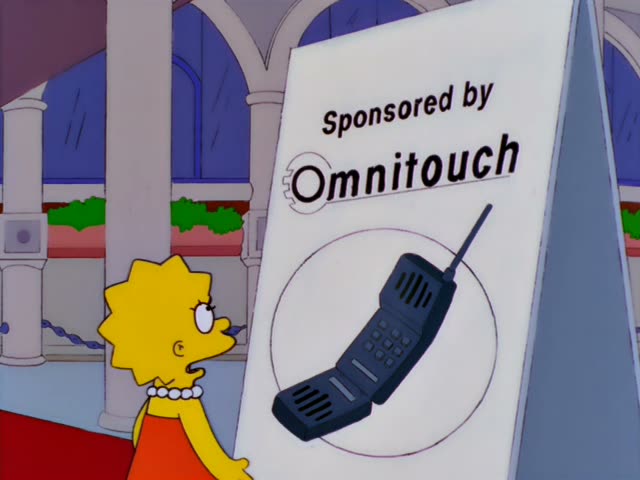 Lisa stands on a red carpet beside a tall sign reading "Sponsored by Omnitouch" with a large cell phone graphic