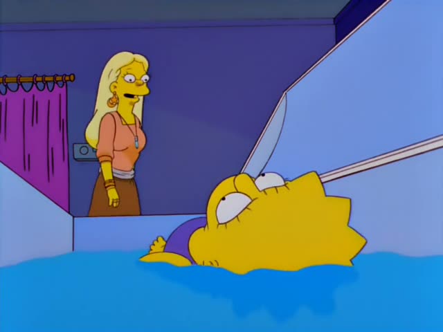 Lisa lies submerged in blue water inside a white tank while a tall blonde woman in an orange top and brown skirt stands…