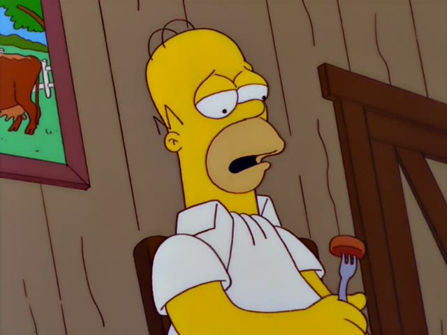 Homer sits in a wooden chair in a barn holding a fork with a piece of meat, staring blankly with his mouth open