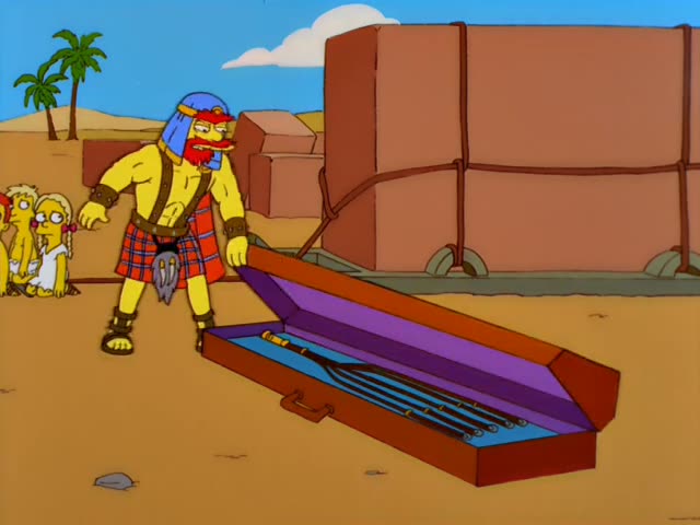 A muscular, red-bearded taskmaster in a plaid kilt and blue headwrap opens a wooden chest in a desert and lifts out…